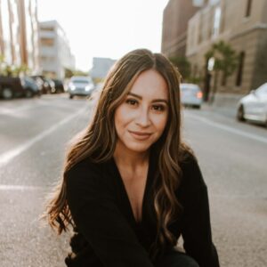 woman in black blazer and blue denim jeans sitting on road during daytime